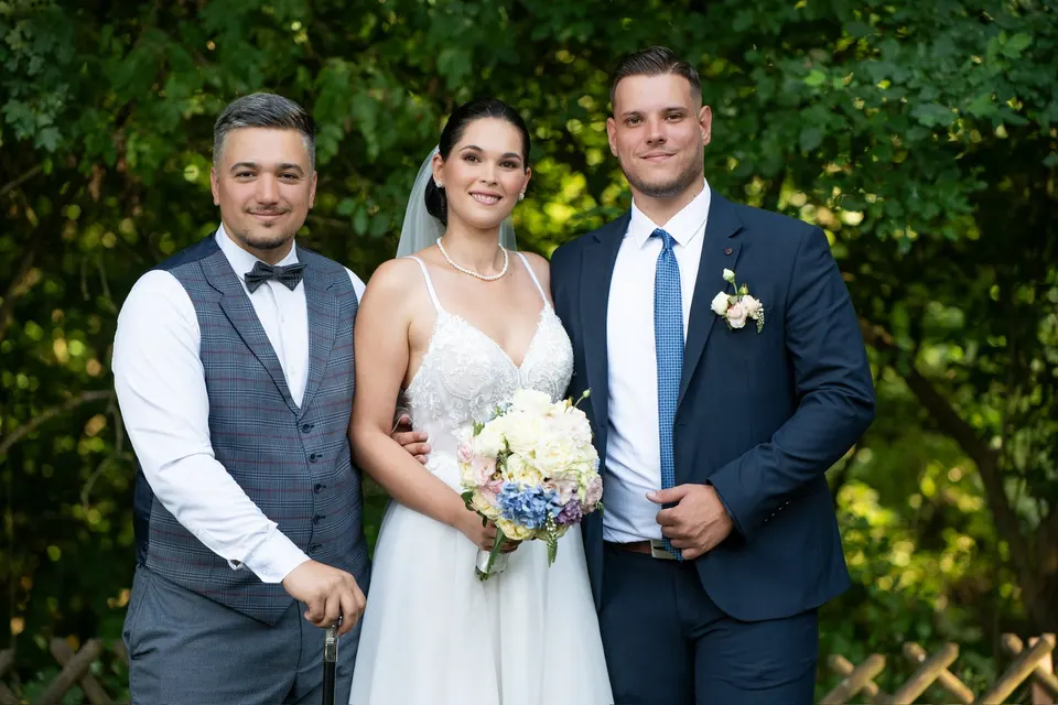 Patrik egy menyasszonnyal és vőlegénnyel egy zöld kertben